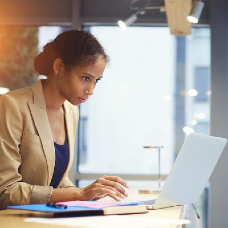 Portrait of concentrated female administrative manager monitoring fate of official site while monitoring work of freelancers sitting in coworking space using laptop computer and wireless connection